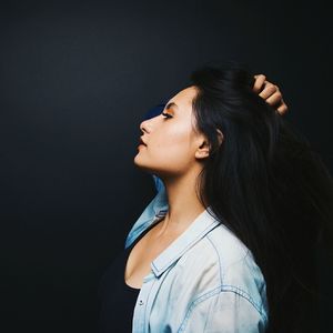 Close-up of young woman over black background