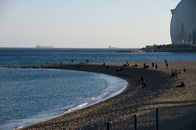 People on beach against clear sky