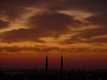 Silhouette of buildings against cloudy sky during sunset
