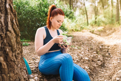 Young woman eating salad in forest