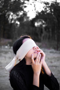 Woman with blindfold against trees in forest