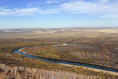 The quiet winding river is flanked by beautiful yellow prairie