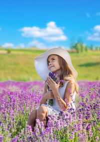 Cute girl holding flowers sitting at farm