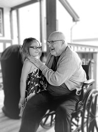 Cheerful grandfather with granddaughter sitting on wheelchair