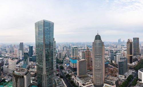 Aerial view of buildings in city against cloudy sky