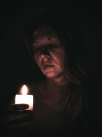 Close-up of woman holding candle in darkroom