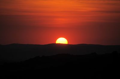 Scenic view of silhouette mountain against orange sky