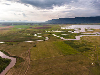Scenic landscape aerial view of field river and basin against a natural mountain