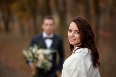 Portrait of young woman standing against plants