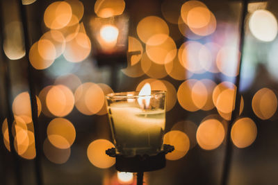 Close-up of lit candles on glass