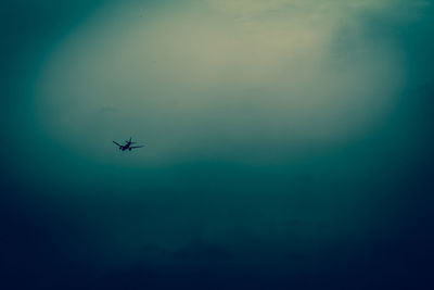 Low angle view of silhouette airplane flying in sky