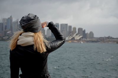 Rear view of woman shielding eyes while looking at sydney opera house