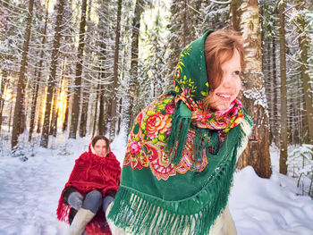 Portrait of smiling young woman standing in snow