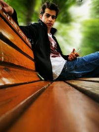 Portrait of young man sitting on wood