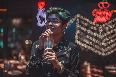 Full length of smiling man holding drink at night