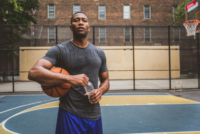 Portrait of male athlete with basketball and water bottle