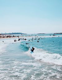 People enjoying at beach against clear sky