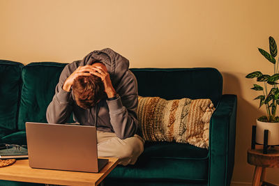 Frustrated man sitting on the couch in his living room in front of laptop. frustration,  depression