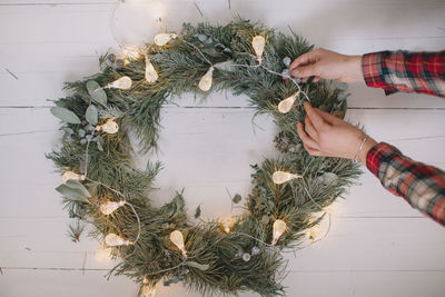 Cropped hands holding illuminated christmas decoration on wall