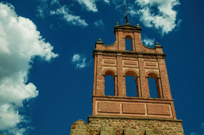 Stone city wall with merlons and tower made by bricks, in a sunny day at avila, spain.