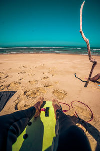 Low section of person on beach against sky