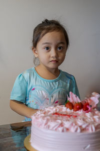 Portrait of cute girl with cake on table at home