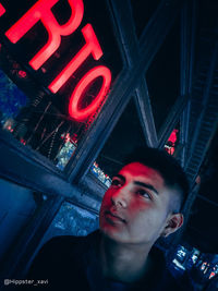 Portrait of young man against illuminated wall