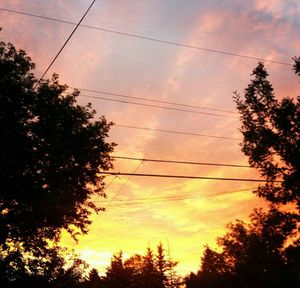 Low angle view of electricity pylon at sunset