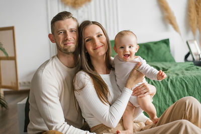 Portrait of mom, dad and six-month-old baby son in their arms spending time together 