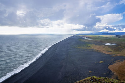 High angle scenic view of famous black sand beach against blue cloudy sky