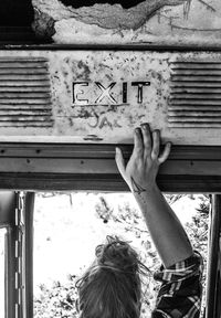 Cropped hand of woman touching exit sign in bus