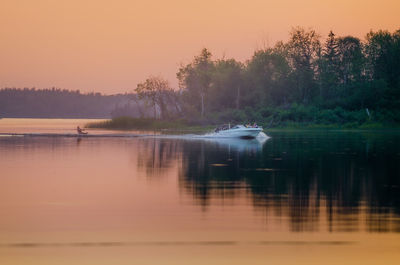 Woman wakeboarding on lake during sunset