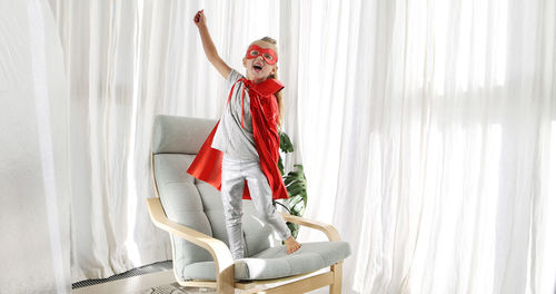 Little girl in superhero costume with mask playing in living room