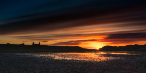 Scenic view of sea against dramatic sky during sunset