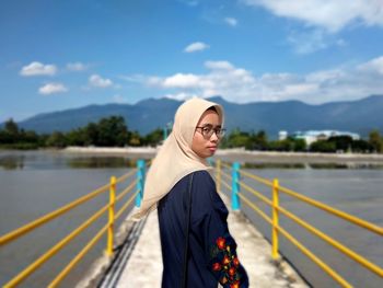 Woman standing by railing against lake