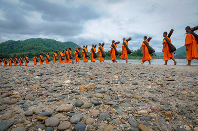 Monks carrying wood while walking by lake