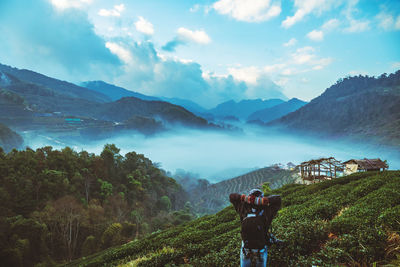 Rear view of man standing on mountain against sky