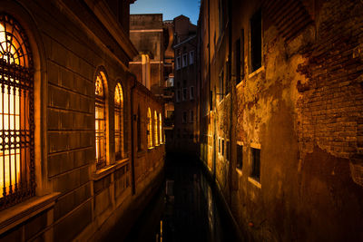 Canal amidst buildings in city at night