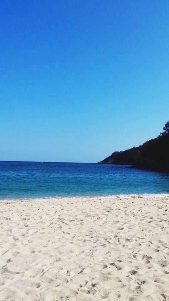 beach, clear sky, sea, sand, copy space, tranquil scene, water, tranquility, blue, shore, scenics, beauty in nature, nature, horizon over water, idyllic, coastline, non-urban scene, remote, vacations, day