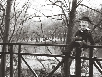 Portrait of man standing by railing against bare trees