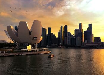 Modern buildings in city against sky during sunset