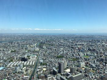 High angle view of city buildings against blue sky