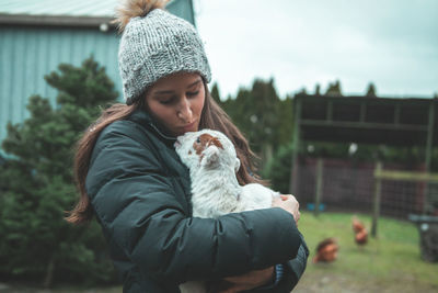 Woman carrying kid goat in farm