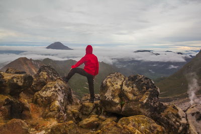 Rear view of man standing on rock against sky