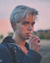 Close-up portrait of young man smoking cigarette during sunset