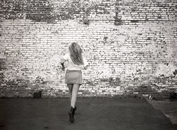 Portrait of woman standing against brick wall