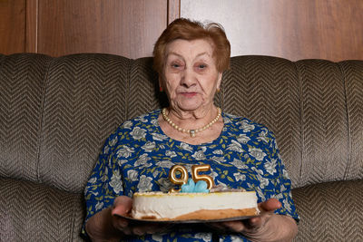 Portrait of old lady sitting on sofa at home