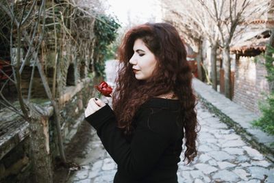 Woman standing by tree with umbrella