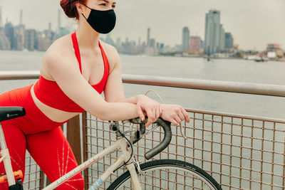 Young woman with bicycle on railing in city