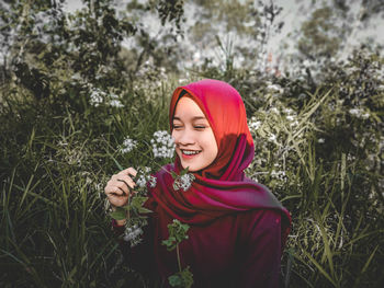 Portrait of smiling young woman against plants